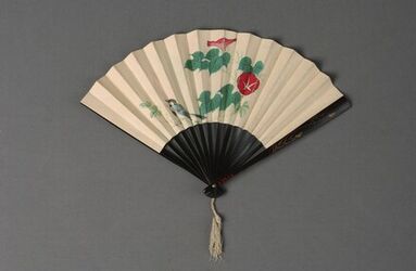 Waaier met zwart gelakt montuur met in goud geschilderde grassen, wit touw met kwast; blad in papi...