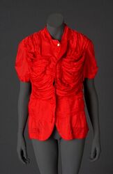 Bloeze met V-hals en reverskraag en korte mouwen in helrode kunstzijde; model met schootpanden en ...