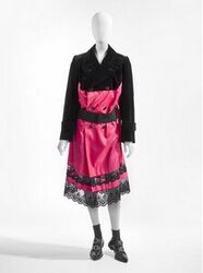 A. Bustier in zwart katoenfluweel, zwart elastiek en zwarte tule
B. Japon in jasvorm in helroze ke...