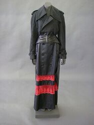 A. Jas in zwart keperweefsel in kunstvezel, met onderaan twee stroken rode, machinale kant; bovena...