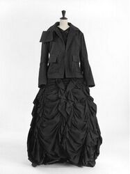 Korte zwart katoenen jas met ingeweven rozenmotieven, met reverskraag waarvan de kraag rechts eind...