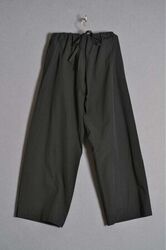 Wijde lange broek in zwart katoen, met een steekzak op de heup langs weerszijde; opgehouden door e...