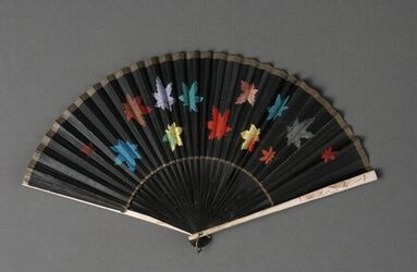 Waaier met een zwart geschilderd montuur met witte buitenbenen waarop gouden irissen; zwart papier...