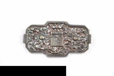 Sierspeld; rechthoek in wit metaal met een Japans (?) blok met kalligrafie geflankeerd door een bl...